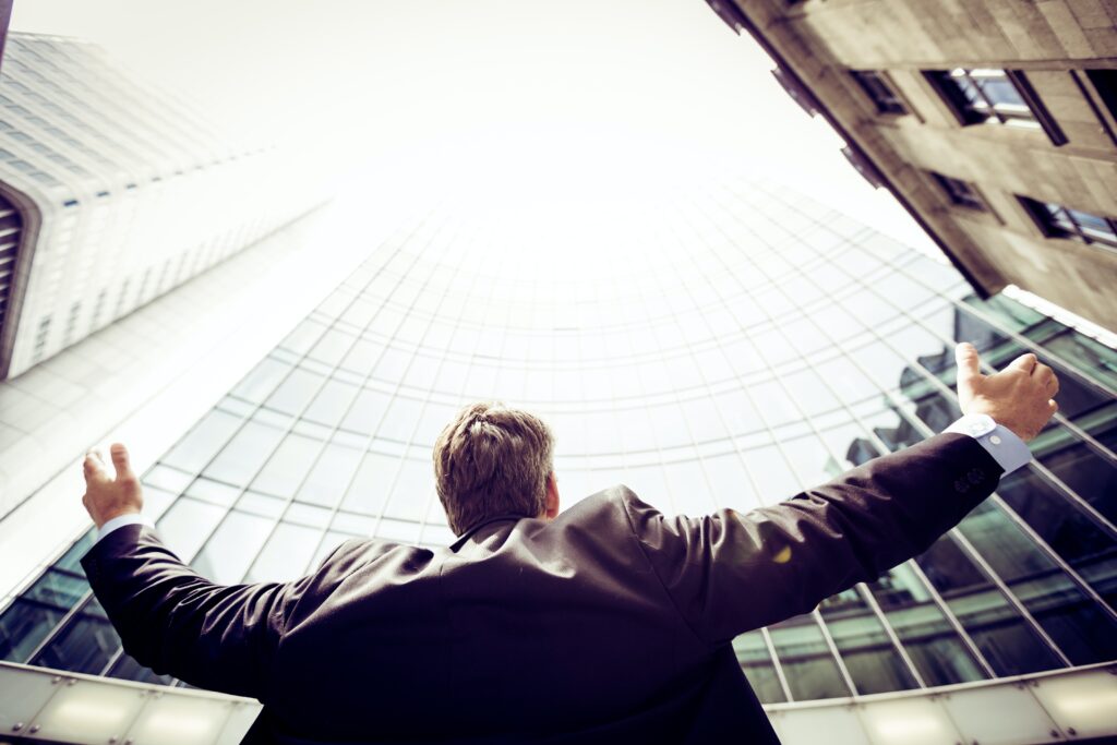 A man rising his hand to the sky near by big building